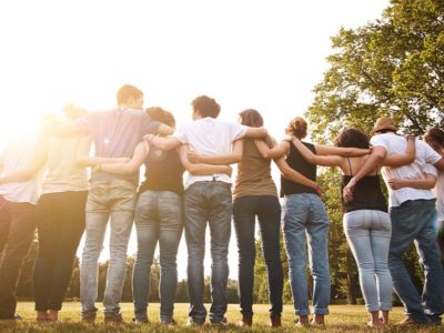 group of coed relapse prevention patients with arms around each other outside